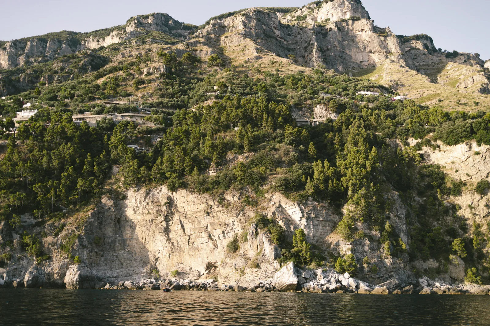 Stunning summer view of Positano's cliffs, showcasing lush greenery and rocky formations.