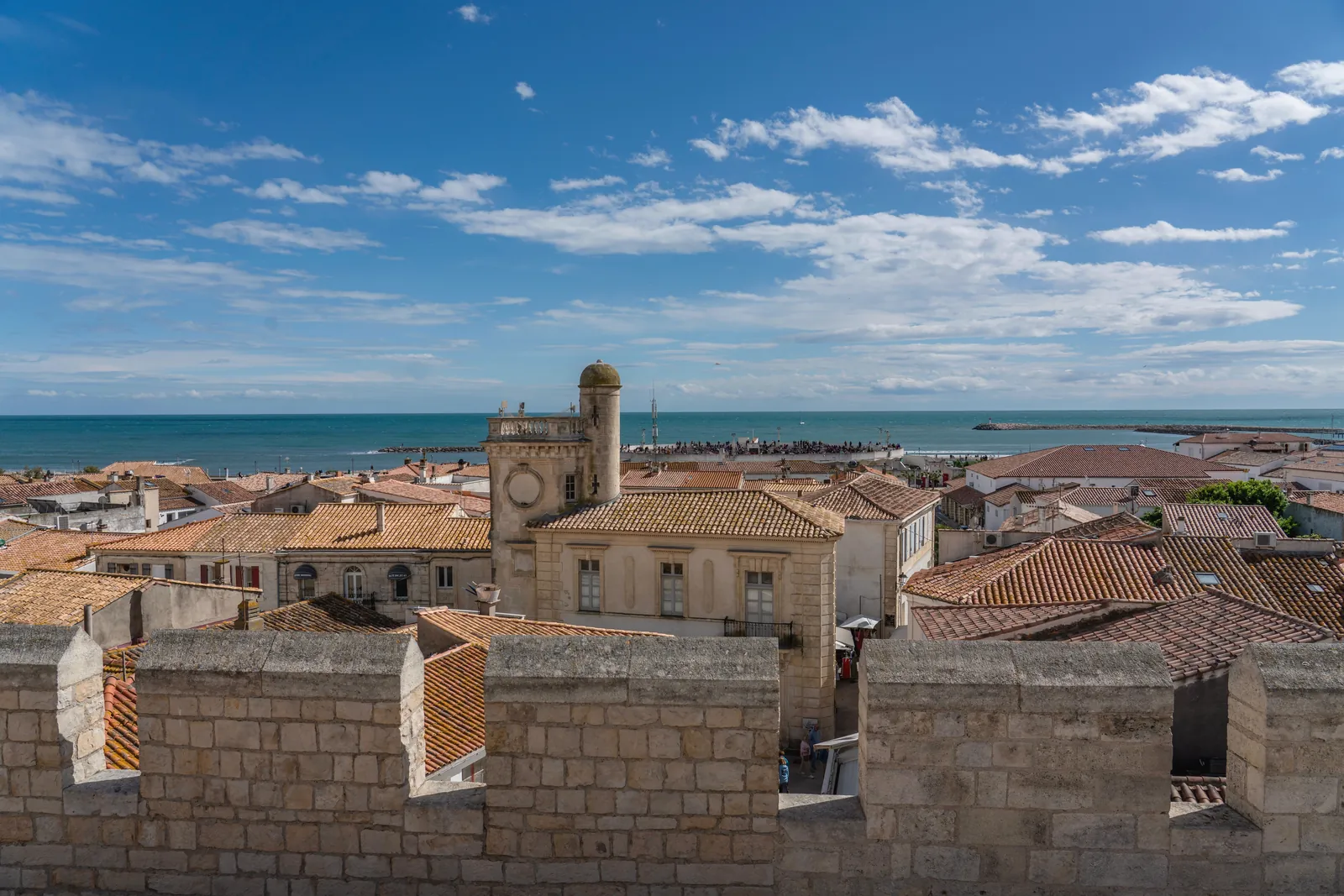 Stunning view of a coastal French village with ocean in the background under a bright blue sky.