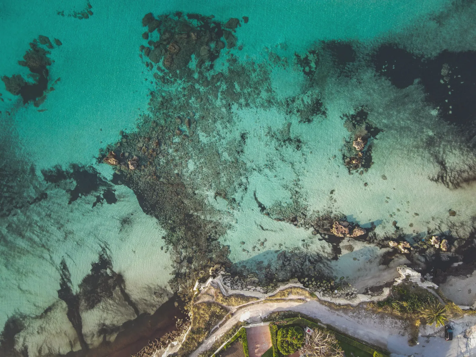 Stunning aerial photograph showcasing the vibrant turquoise waters and rocky coastline.