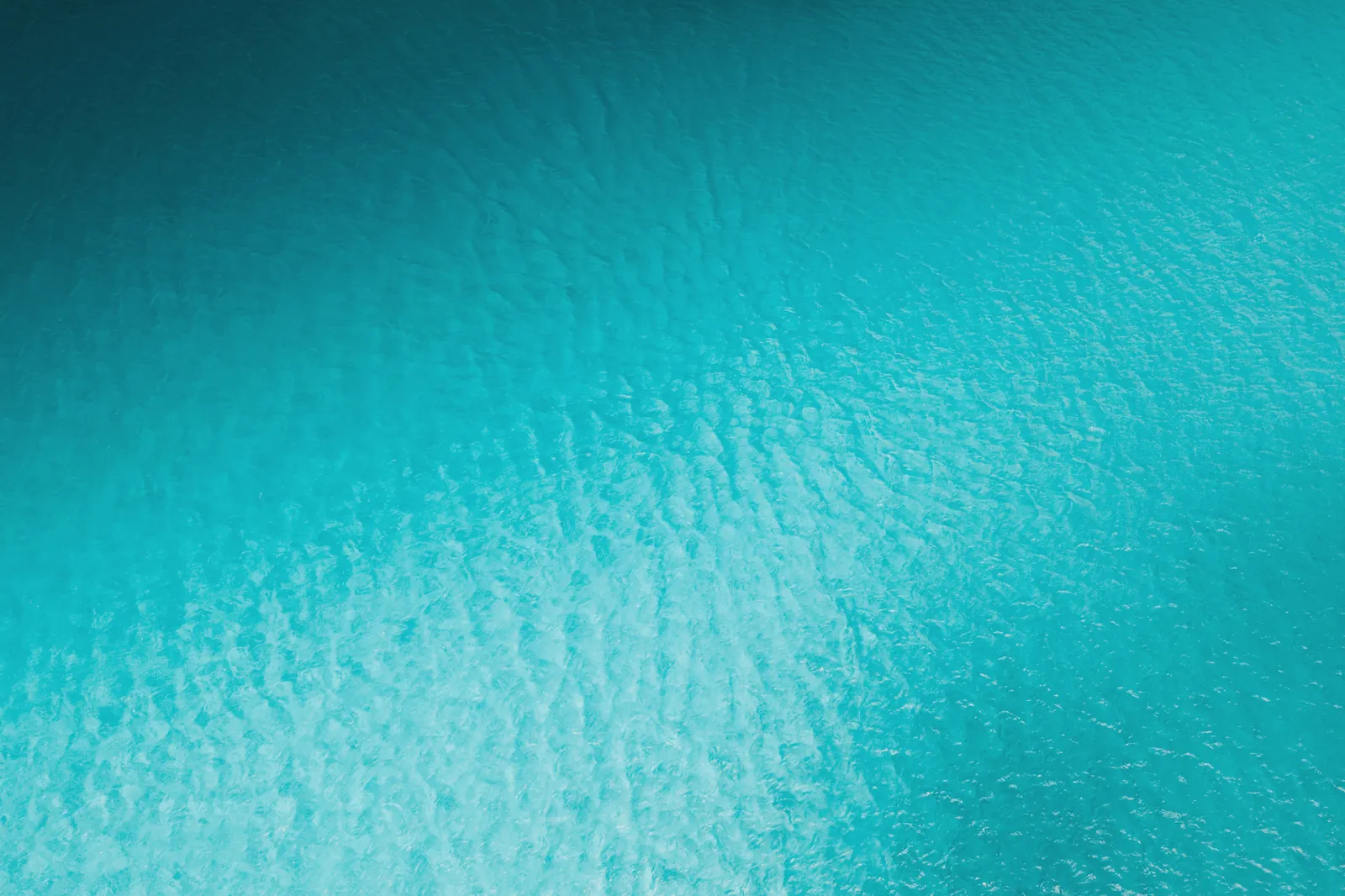 A serene aerial photograph of a textured turquoise water surface, ideal for nature and abstract themes.