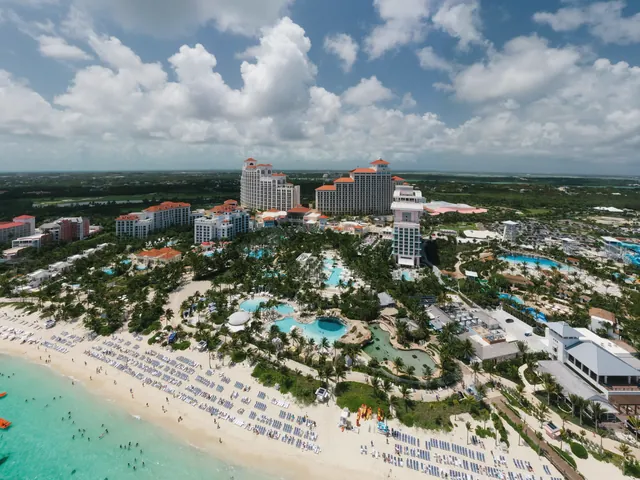 A stunning aerial shot of a luxury resort by the beach in the Bahamas, featuring pools and palm trees.