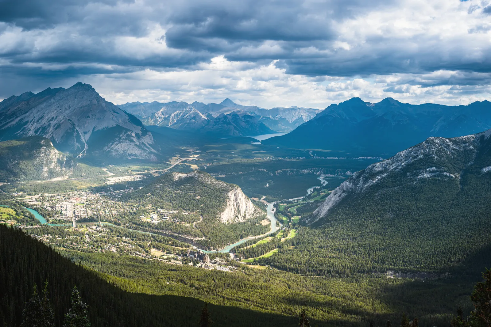 Scenic vista of cloud-covered mountain peaks and lush valleys in Banff National Park.