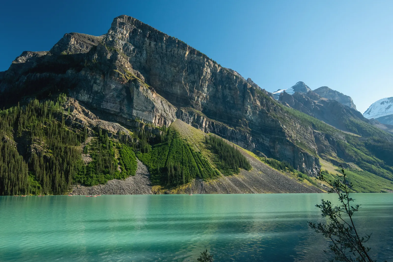 Stunning view of Lake Louise in Alberta, Canada, surrounded by the majestic Rocky Mountains and clear blue sky.