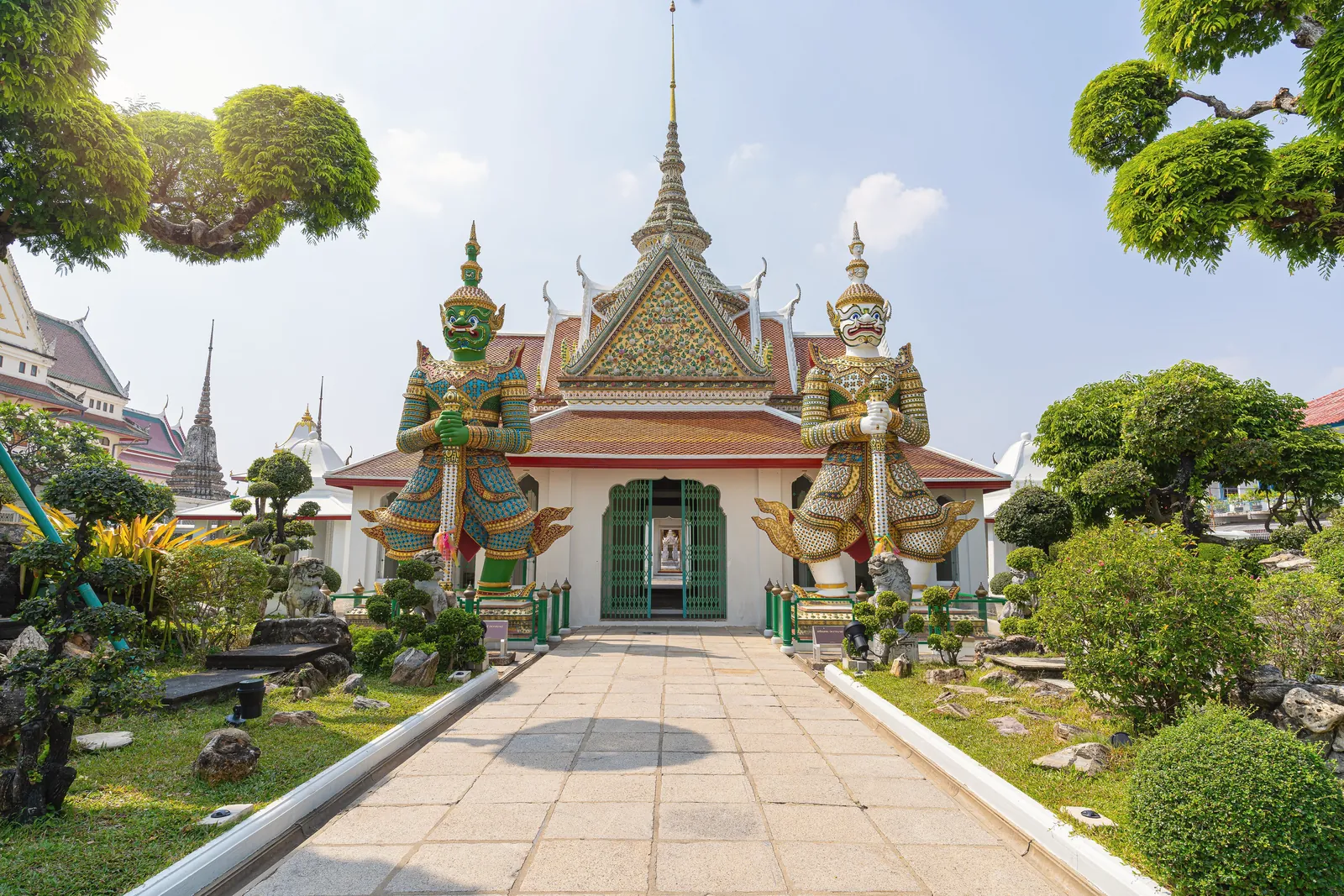 Stunning view of guardian statues at Wat Arun temple in Bangkok, Thailand, showcasing intricate Thai architecture.