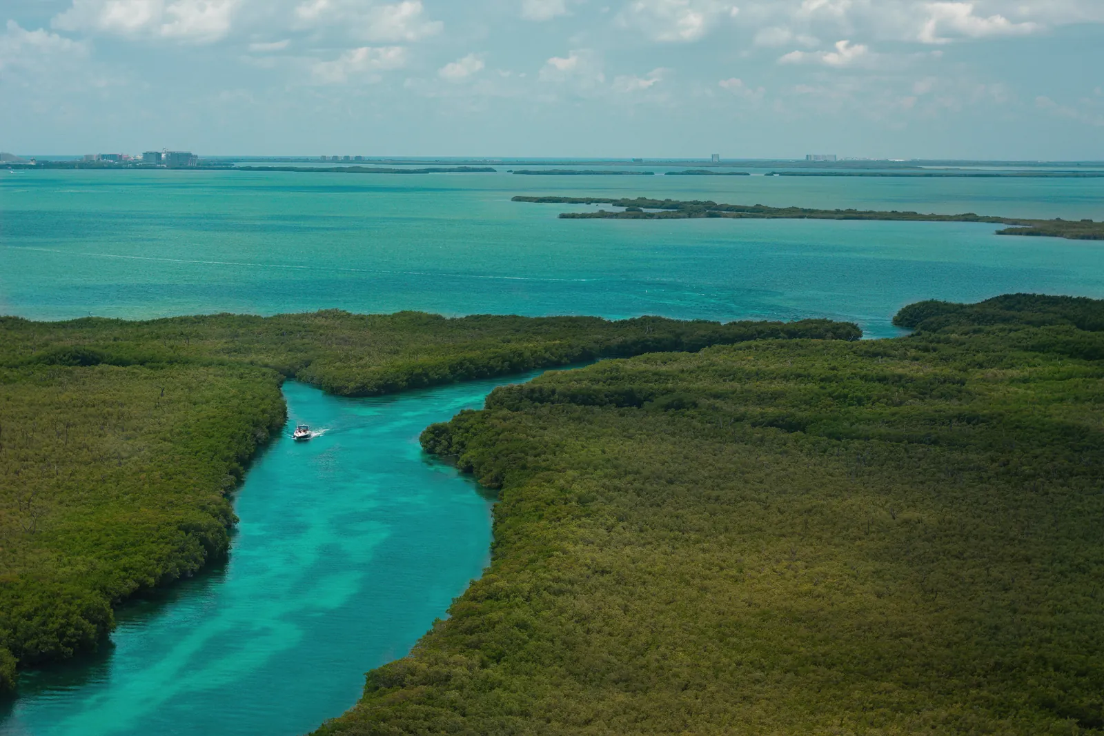 Explore the vibrant green mangroves and azure waters of Cancún from above, capturing natural beauty and tranquility.