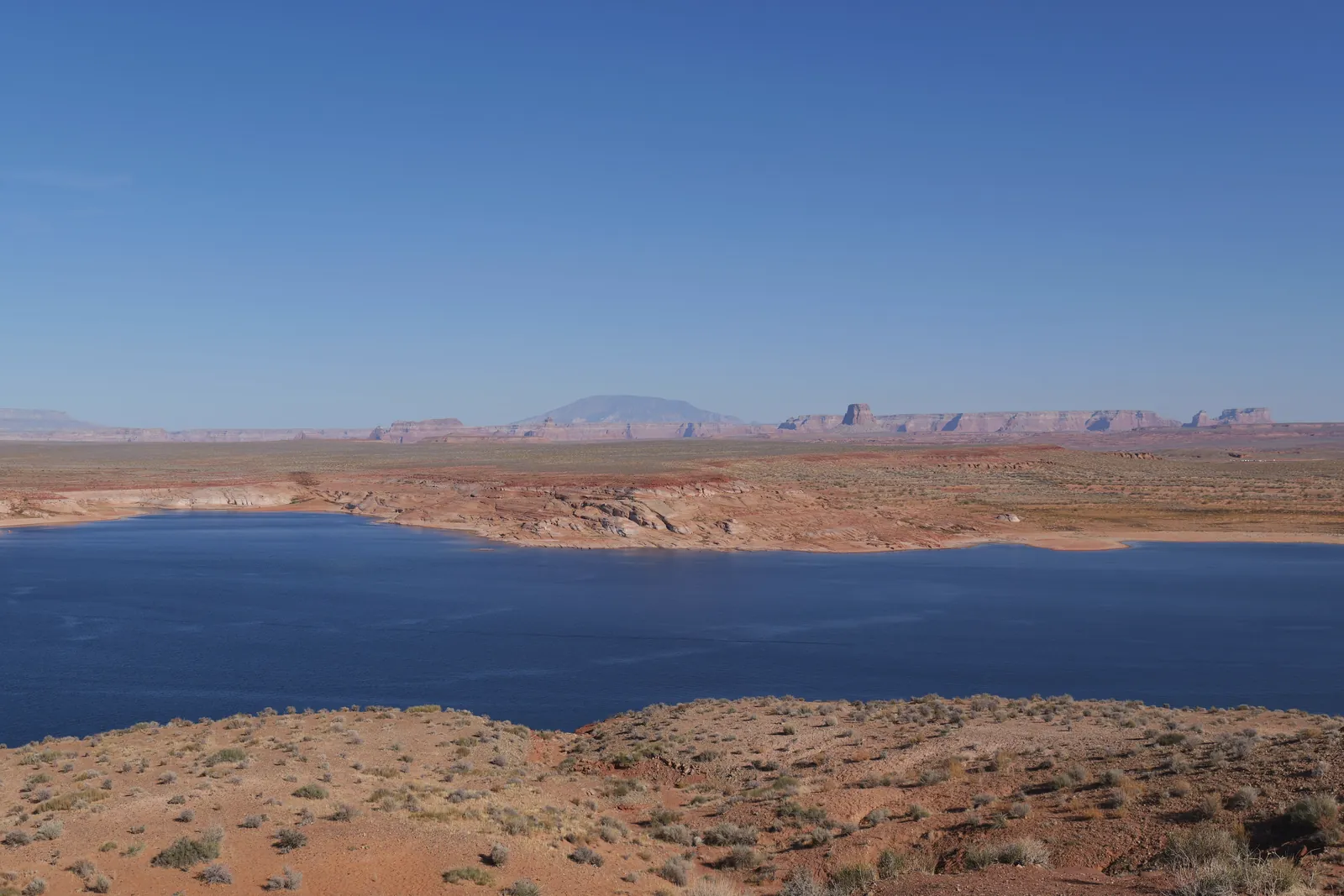 Expansive desert landscape with Lake Powell under clear blue skies. Perfect for travel and nature enthusiasts.