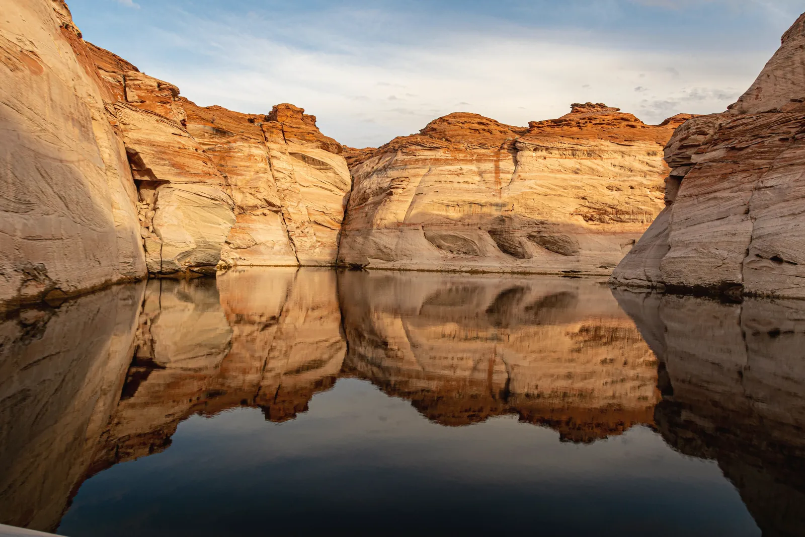 Stunning rock formations reflected in the calm waters of Lake Powell, Utah, at sunset.