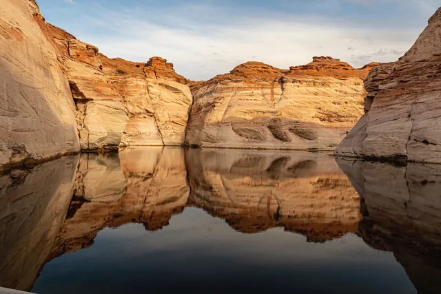 Stunning rock formations reflected in the calm waters of Lake Powell, Utah, at sunset.