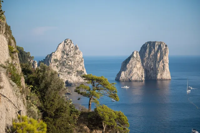 Stunning scenic view of the Faraglioni rock formations and sea in Capri, Italy, under clear blue skies.