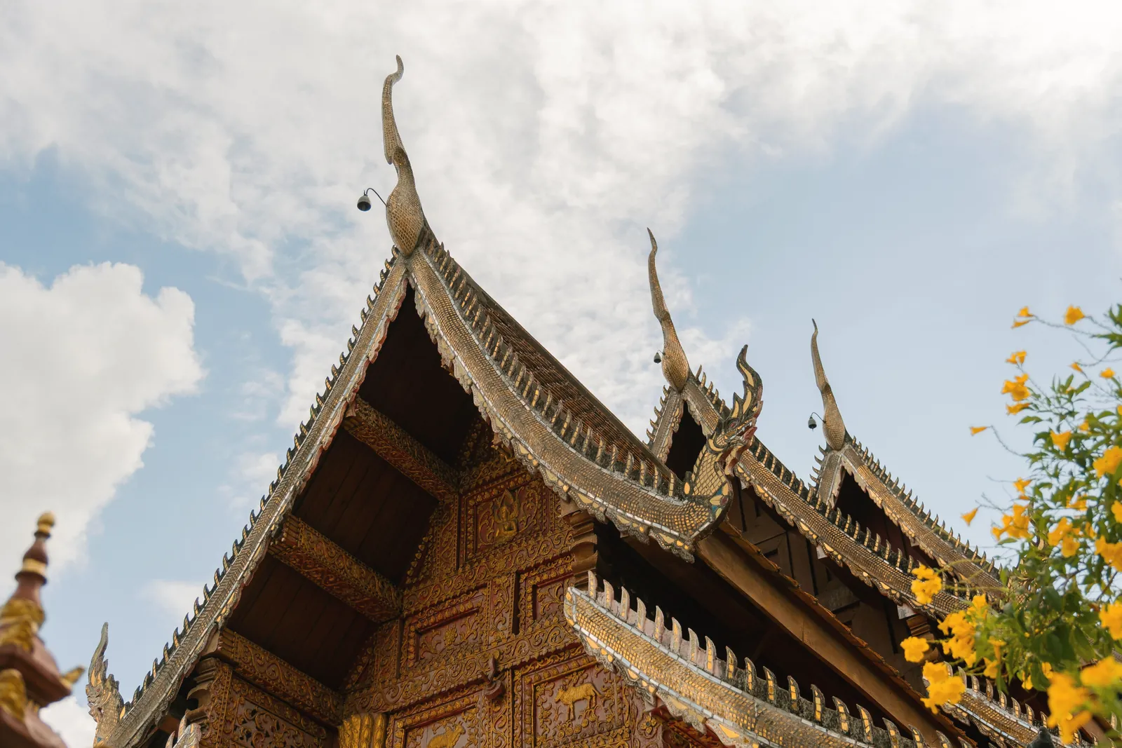 Beautifully ornate temple roof with traditional Thai architecture in Chiang Mai under a clear blue sky.