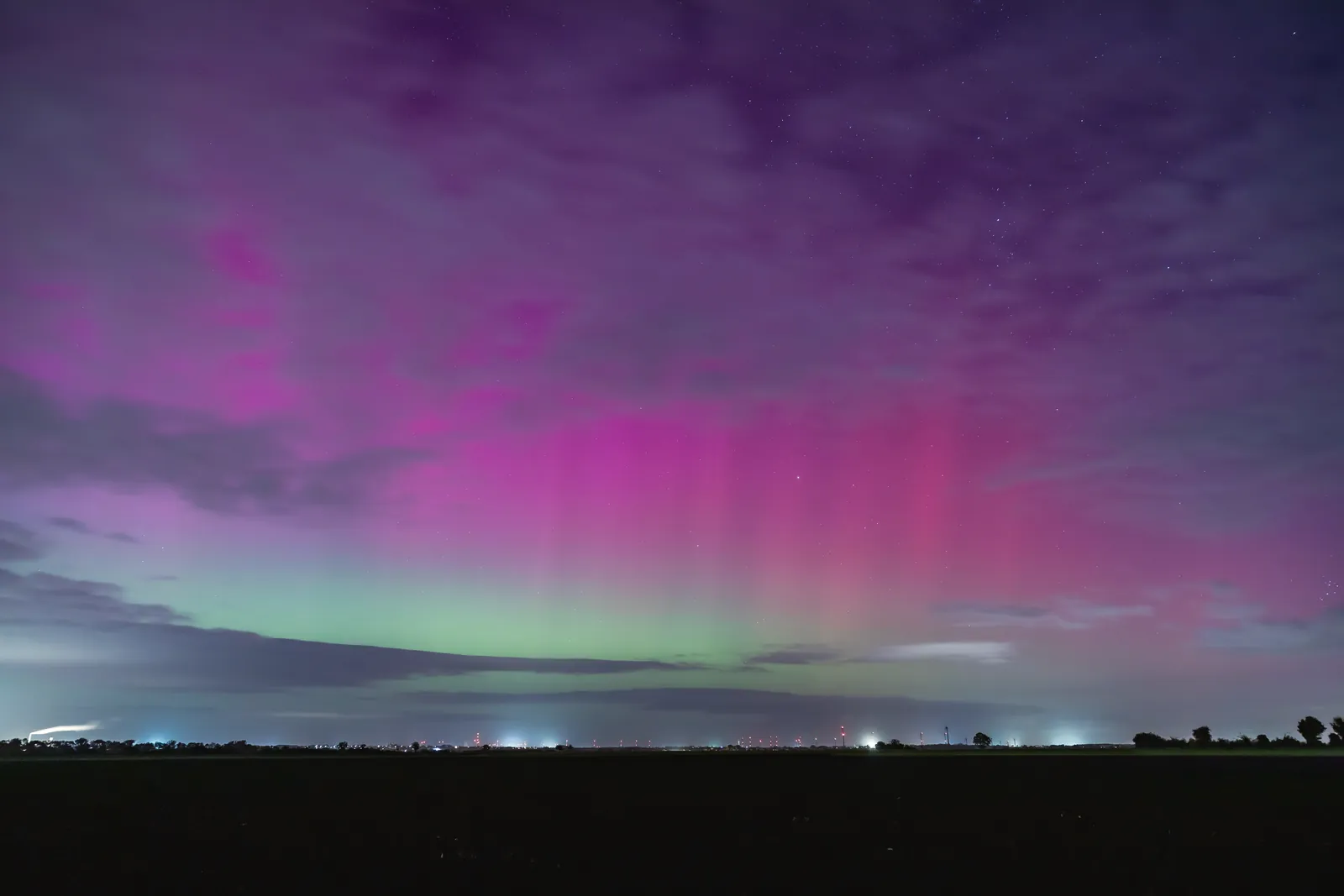 A vivid display of the aurora borealis in the night sky with purple and green hues.