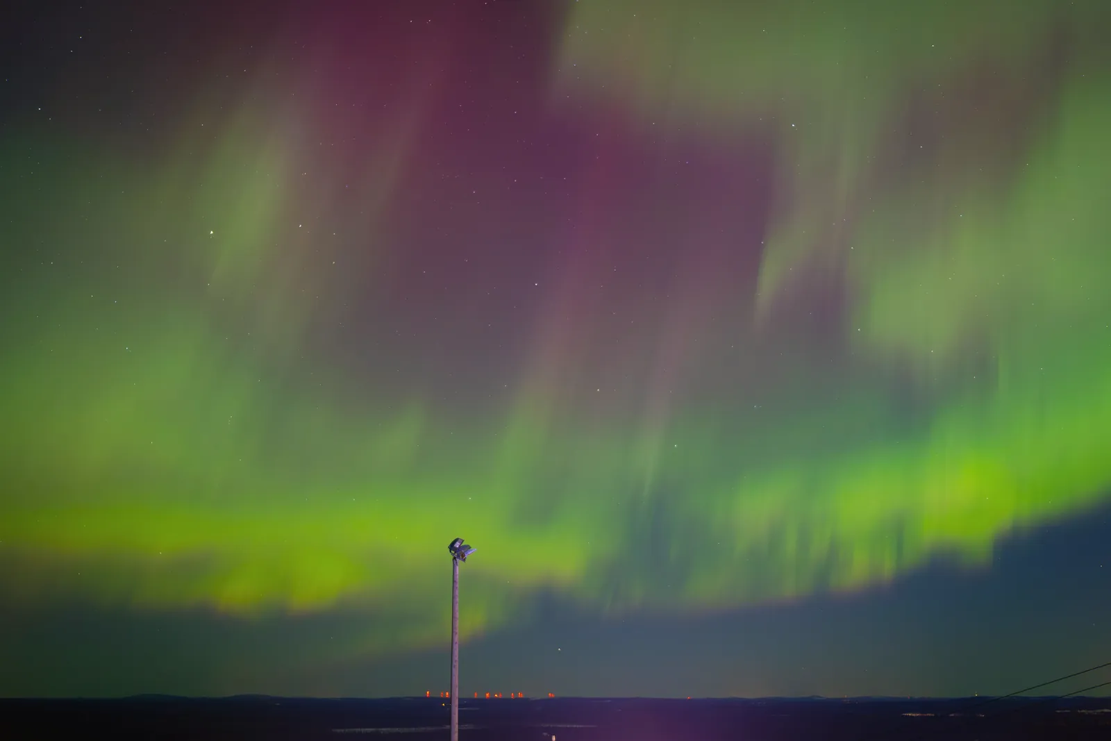 Vivid aurora borealis with vibrant green and purple hues against a starry night sky.