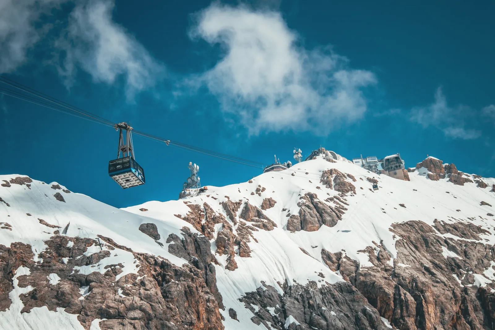 Cable car ascends over snow-covered mountains in a stunning winter landscape.