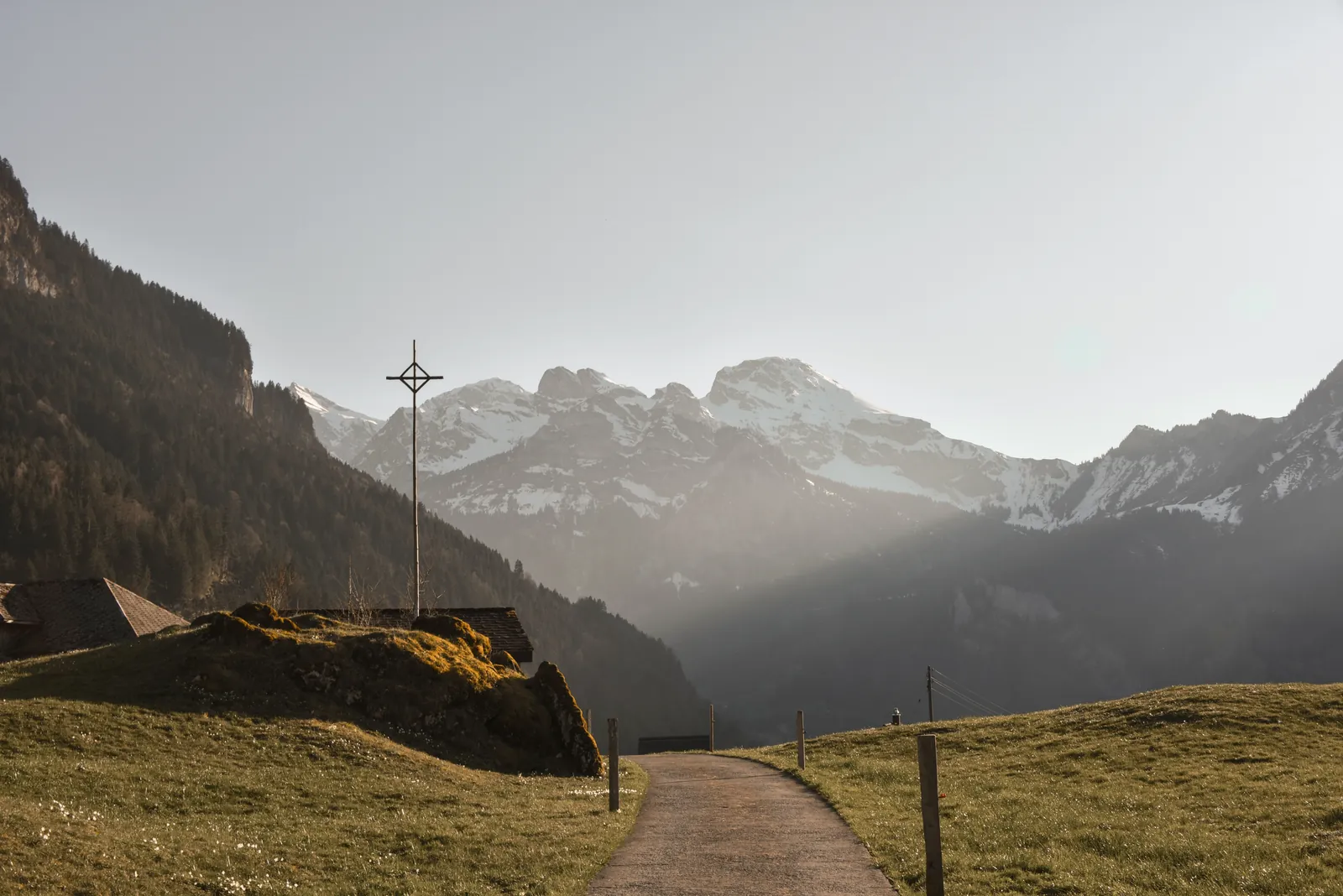 Idyllic scene of a mountain landscape with pathway and cross in Wolfenschiessen, Switzerland.