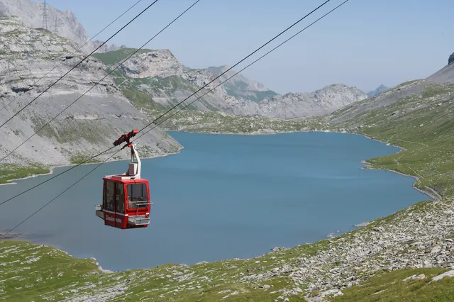 Red cable car sweeping over a blue lake in the stunning Swiss Alps.