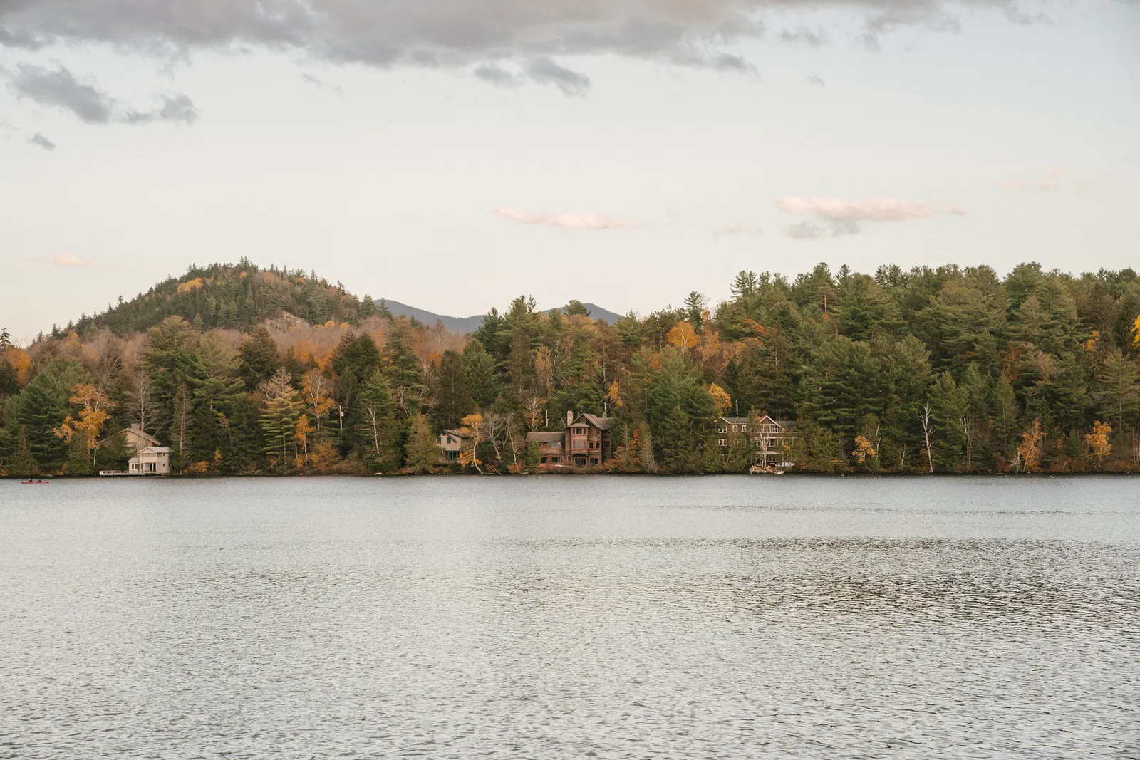 Picturesque scenery of tranquil lake located near small settlement in fall forest in mountainous area