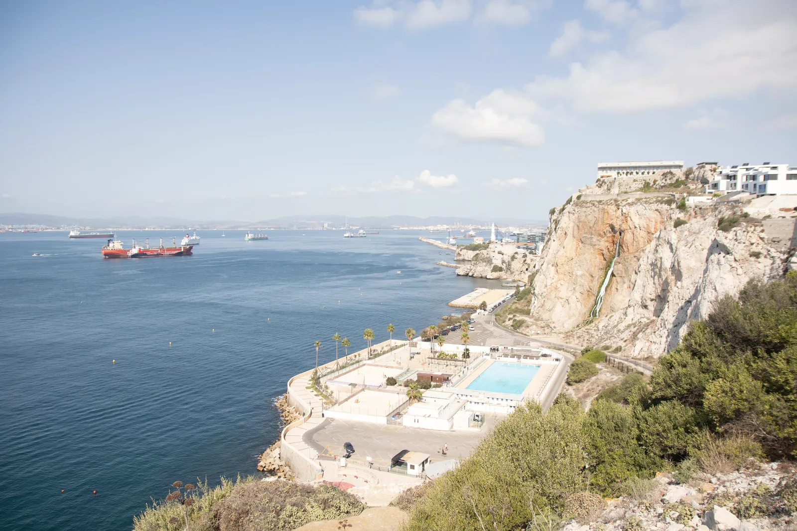 A breathtaking view of the coastline featuring cliffs, a resort, and calm sea waters.
