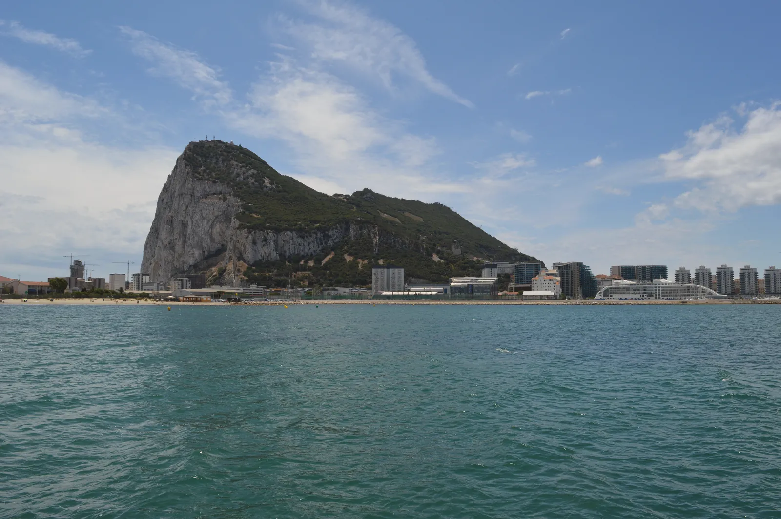 Beautiful view of the Rock of Gibraltar and waterfront buildings under a blue sky.