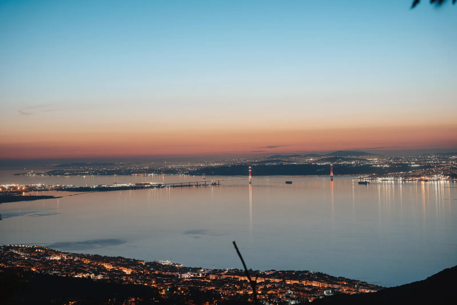 A breathtaking twilight view of a city by the sea with vibrant colors reflecting on the water.