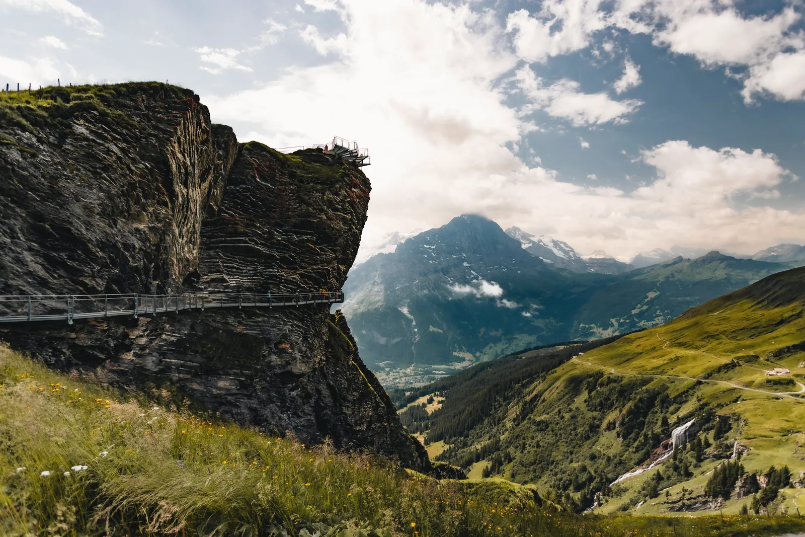 Scenic view of rocky cliffs and lush valleys under a bright summer sky.
