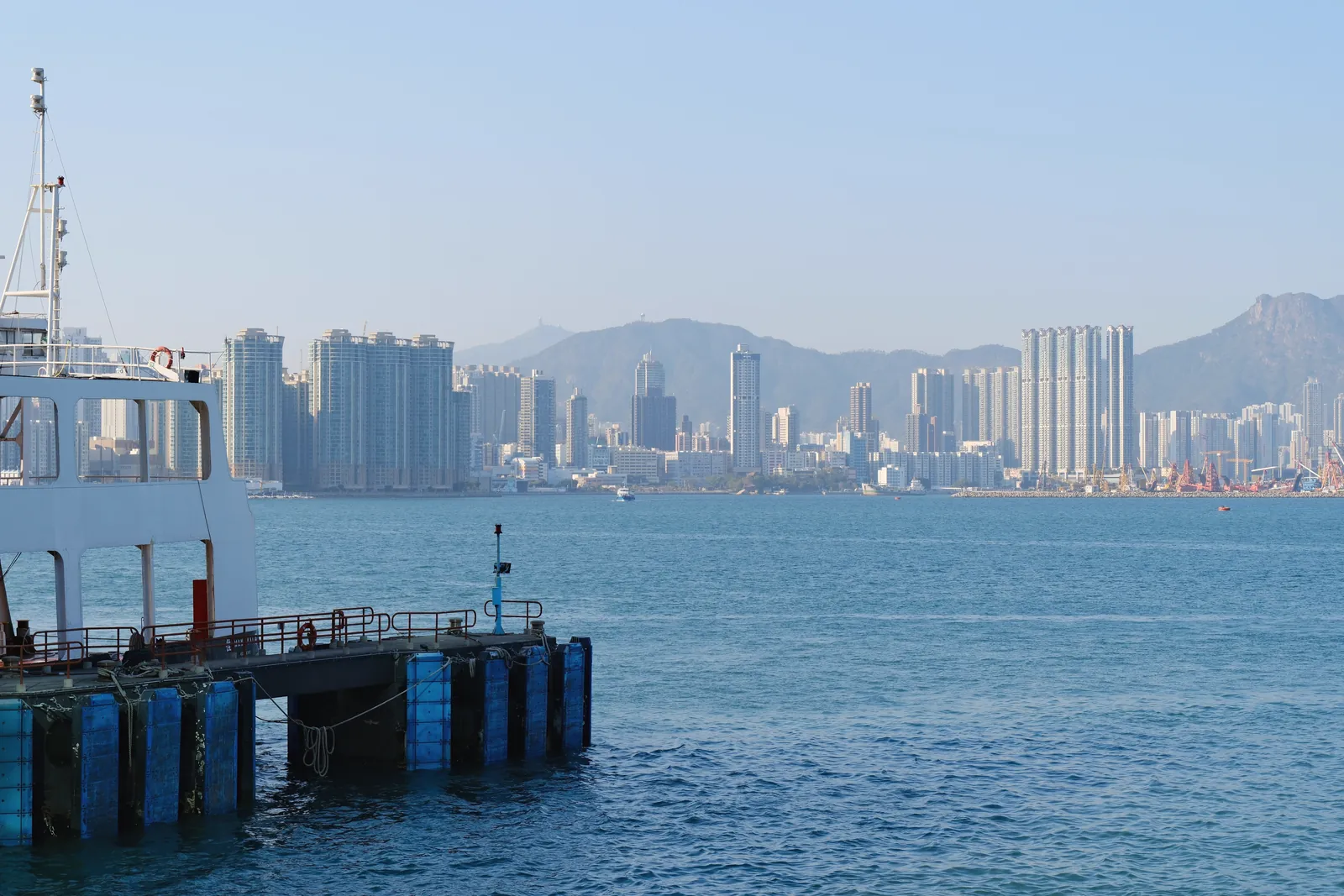 Skyline of Hong Kong with a ferry docked at the harbor, clear day view.