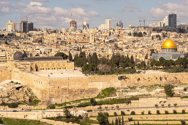 A breathtaking view of Jerusalem featuring Al-Aqsa Mosque and the Dome of the Rock under a bright sky.