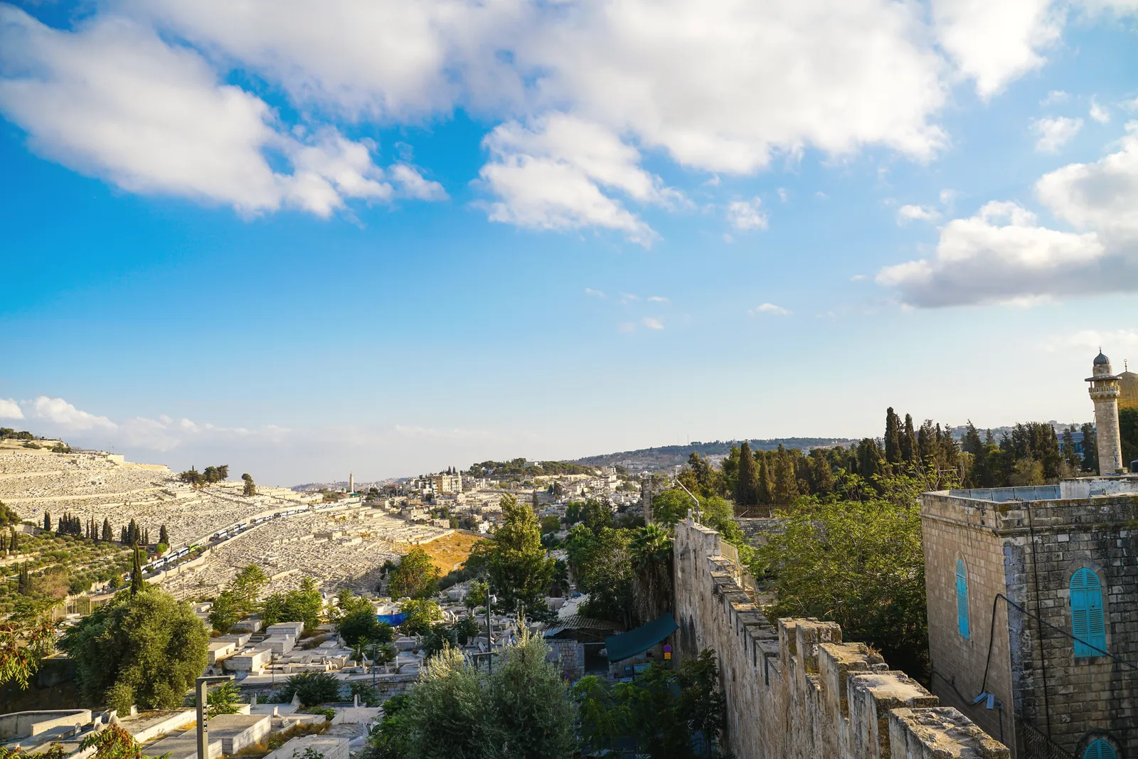 Explore the historic landscape of Jerusalem under a clear blue sky with lush greenery and ancient architecture.
