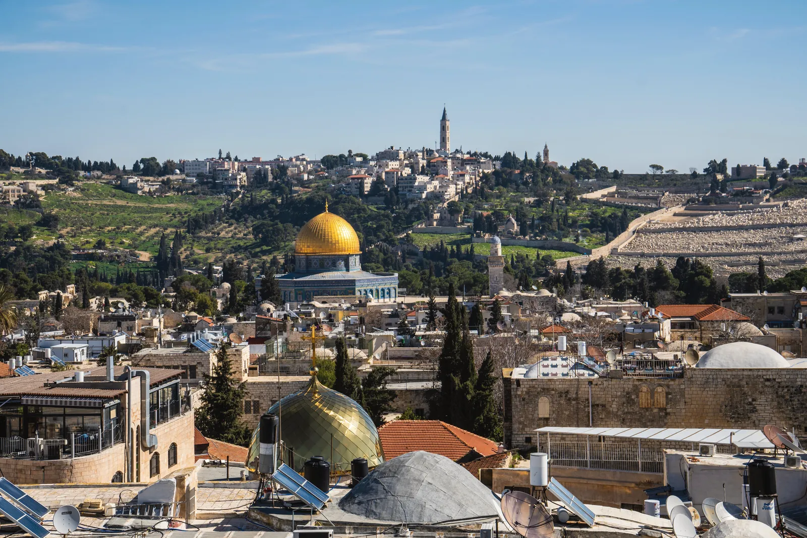 Panoramic view of Jerusalem skyline featuring the Dome of the Rock under a clear sky.