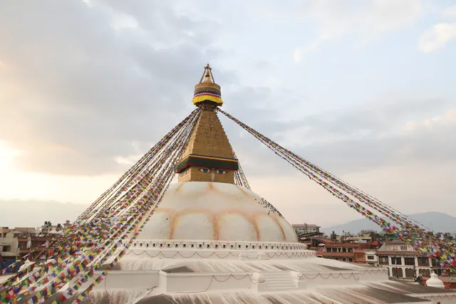 Boudhanath Stupa in Kathmandu with prayer flags at sunrise, symbolizing peace.