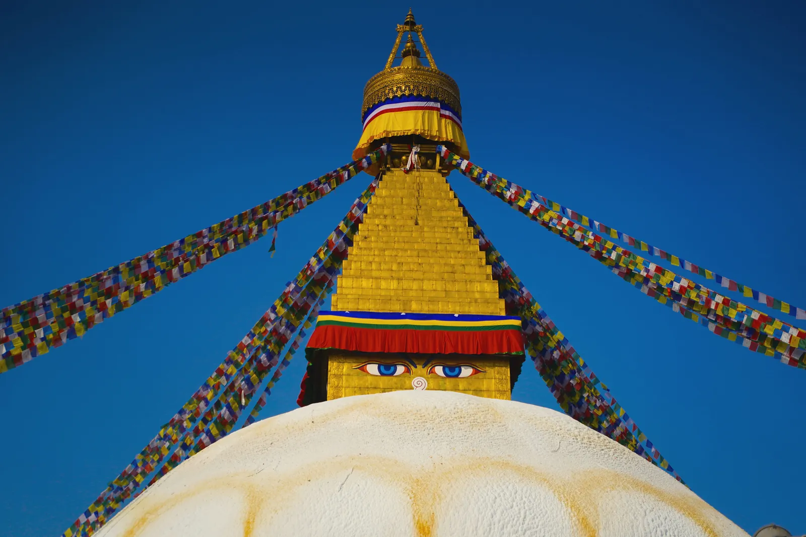 The majestic Boudhanath Stupa in Kathmandu, adorned with prayer flags under a blue sky.