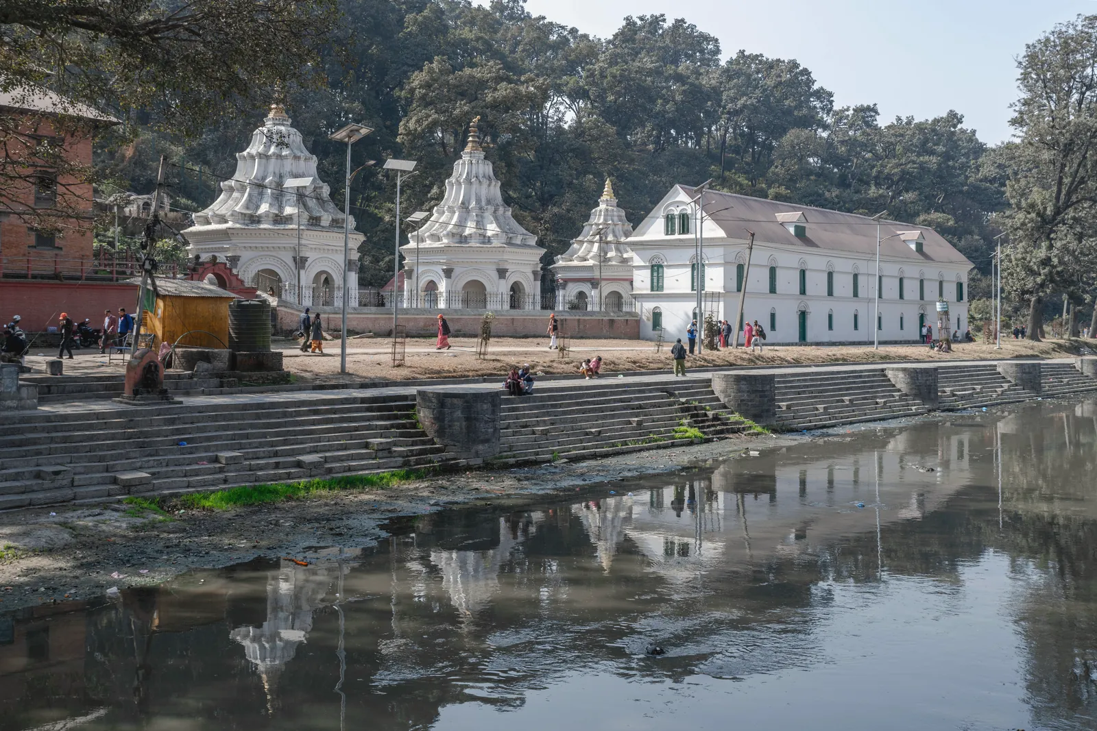 View of historical temples along the riverbank in Kathmandu, Nepal, showcasing traditional architecture.