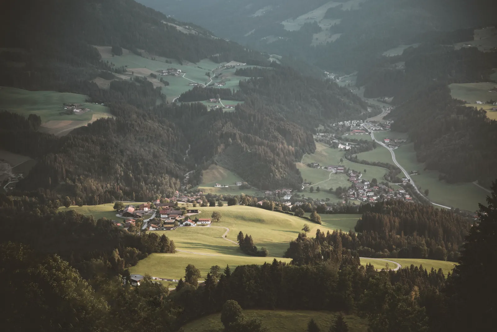 Scenic aerial view of Kitzbühel's lush countryside with mountains and forests.