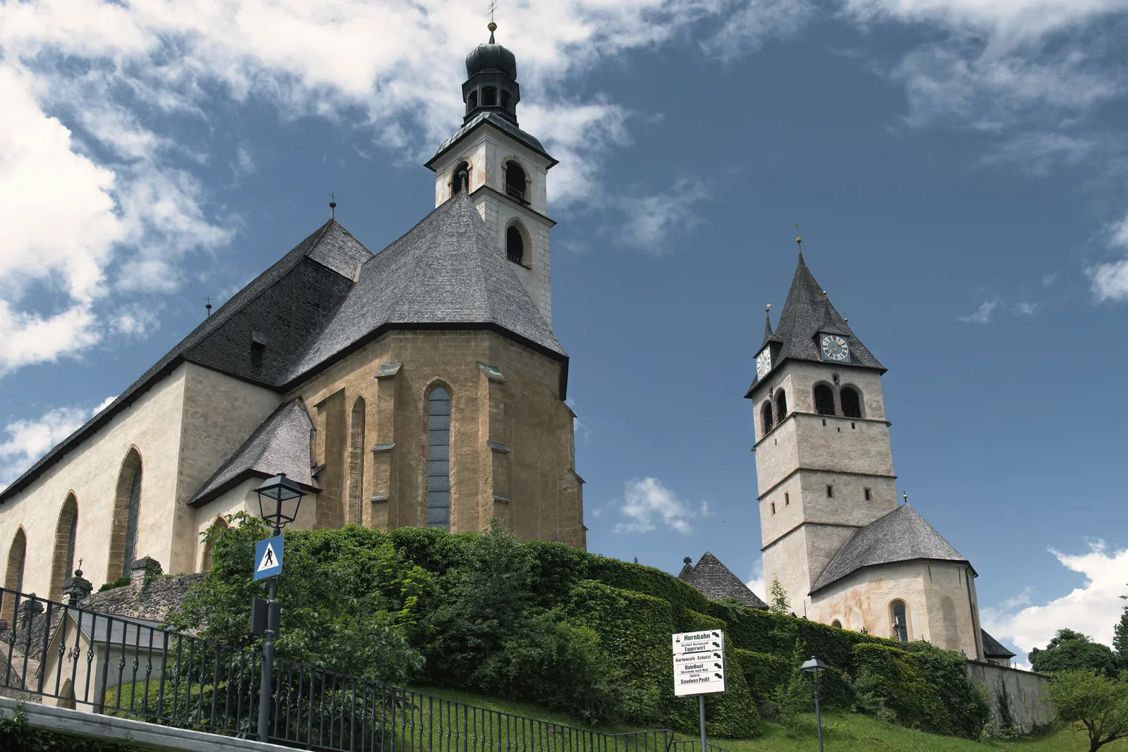 Historic church towers in Kitzbühel, Austria stand tall against a bright blue sky. A landmark view.