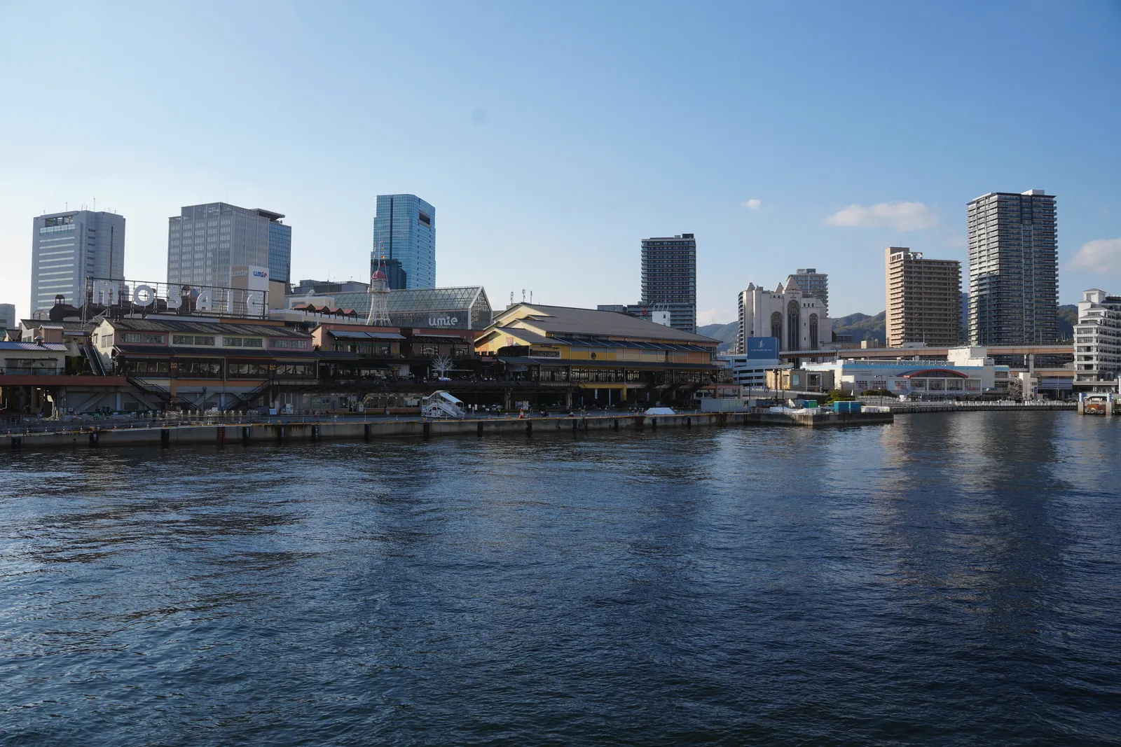 A vibrant city waterfront featuring modern architecture under a clear blue sky.