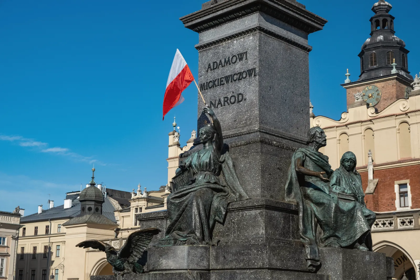 Monument of Adam Mickiewicz in Kraków, featuring Polish flag and historic architecture.