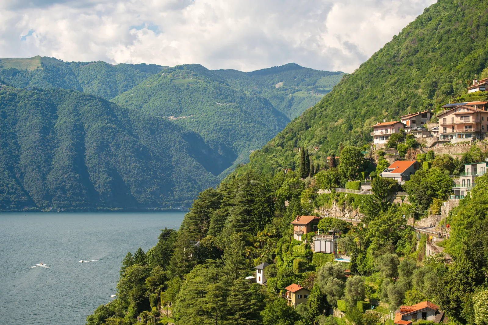 Breathtaking view of Lake Como, Italy, with lush green hills and picturesque villas under a vibrant summer sky.