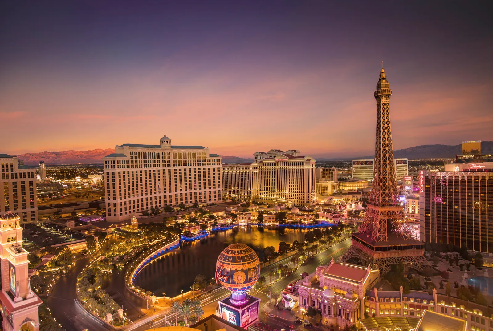 Stunning aerial view of Las Vegas Strip at sunset with iconic Eiffel Tower replica and vibrant cityscape.