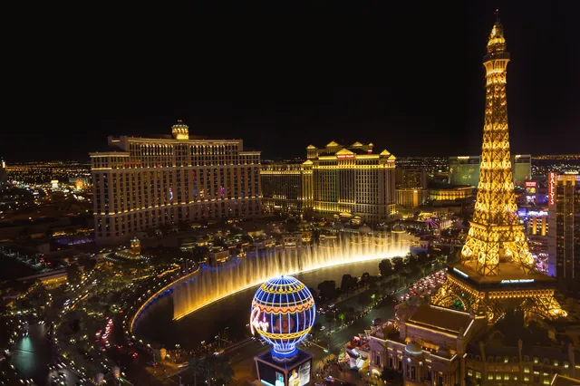 Bright lights of Las Vegas Strip showcasing the iconic Eiffel Tower and Bellagio fountains at night.