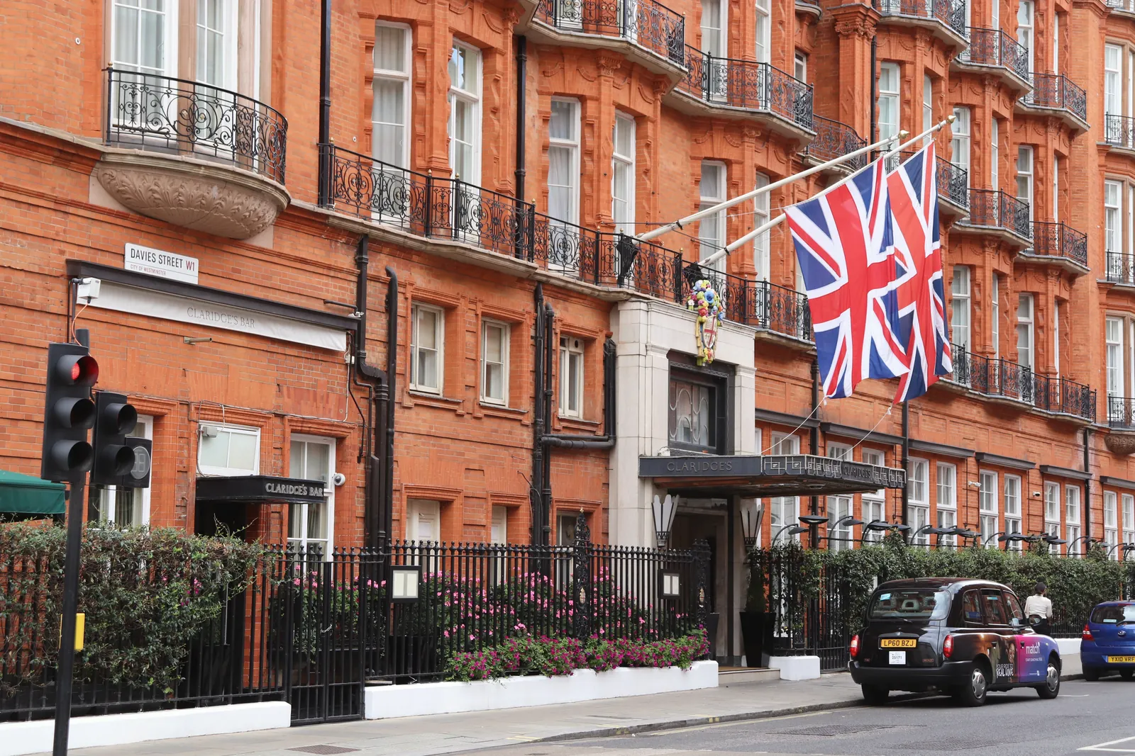 Exterior of classic London hotel on a busy street with Union Jack flags displayed.