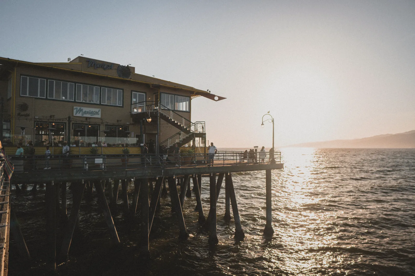 A breathtaking sunset view at a seaside restaurant on Santa Monica Pier, perfect for a summer getaway.