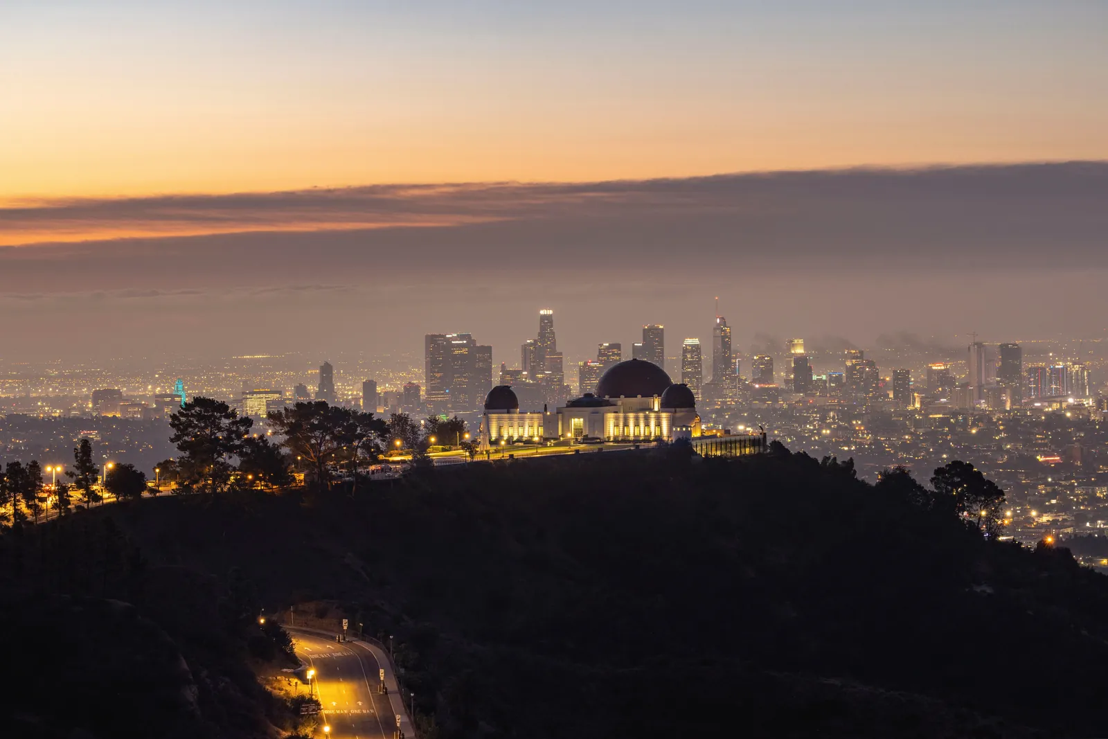 Dramatic twilight view of Griffith Observatory and Los Angeles skyline, showcasing vibrant city lights.