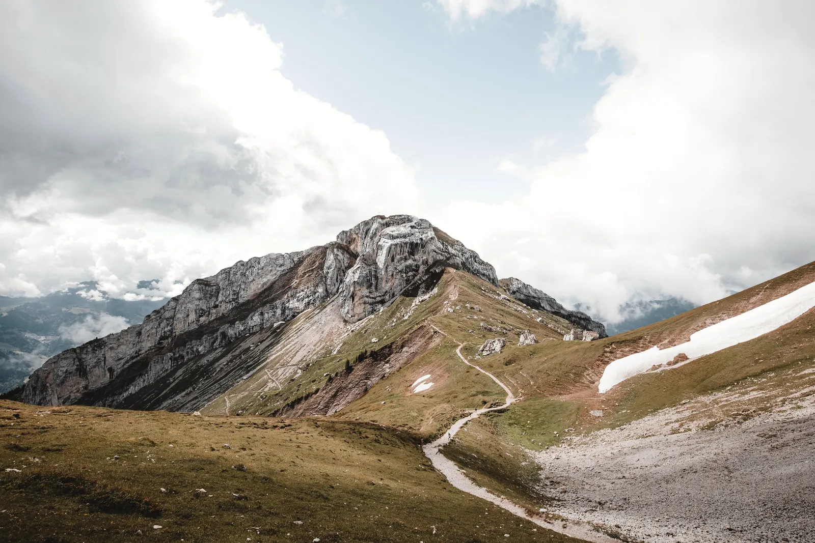 Breathtaking view of rugged Swiss Alps with cloudy sky and meandering path, near Lucerne.