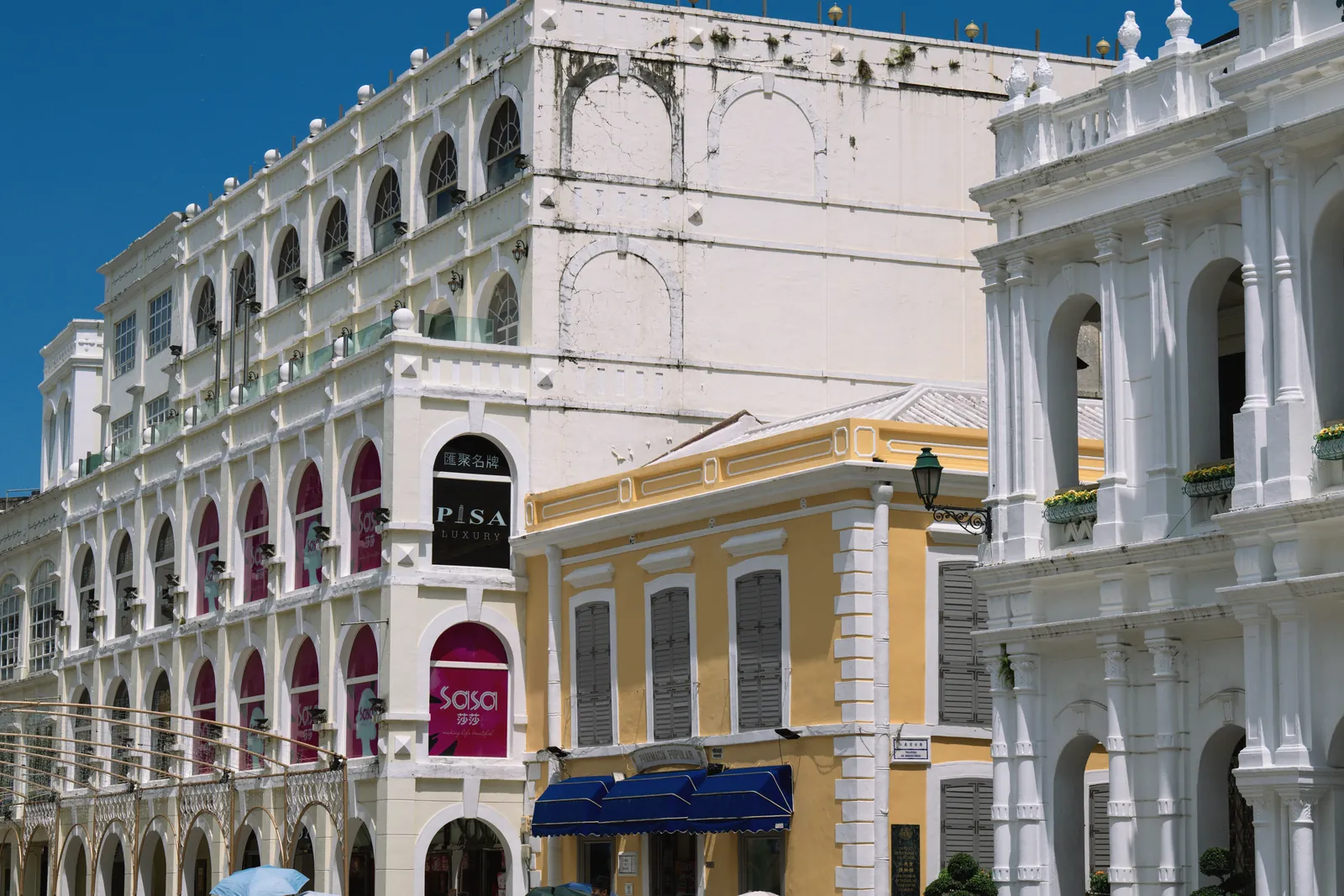 View of historic colonial-style buildings under a clear blue sky in Macau.