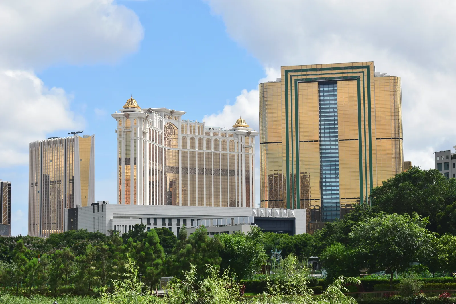 A vibrant view of Macau's skyline featuring iconic golden towers amidst lush greenery.