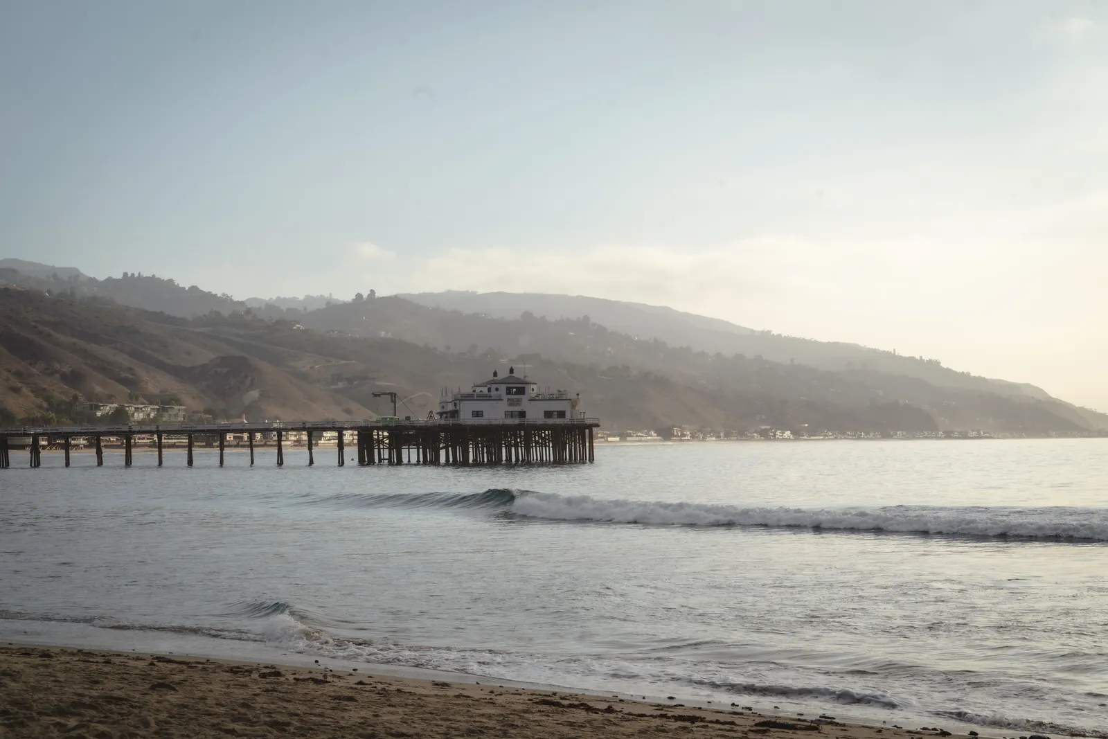 Tranquil morning view of Malibu Pier extending into the ocean with a mountainous backdrop.