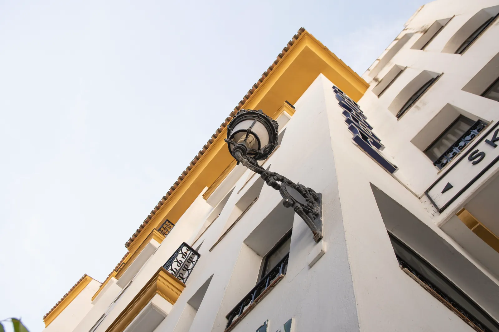 Architectural view of a building in Spain from a low angle, showcasing design elements and a street lamp.