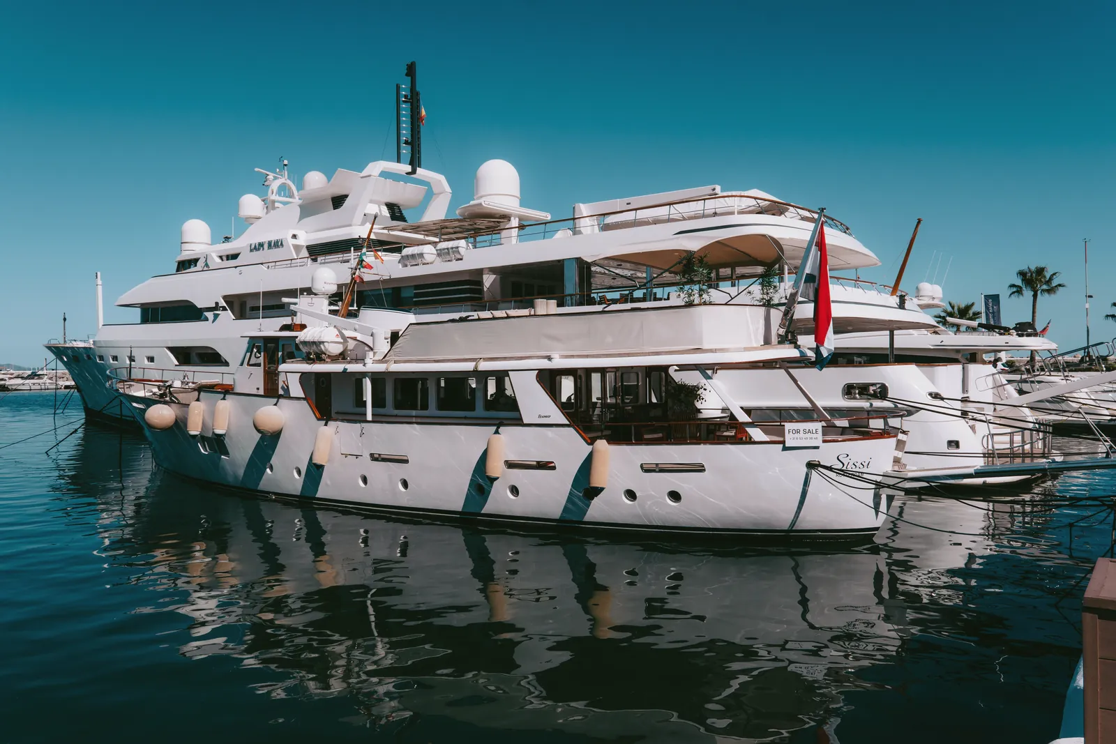 Elegant yachts docked at the picturesque Puerto Banus Marina under a clear blue sky.