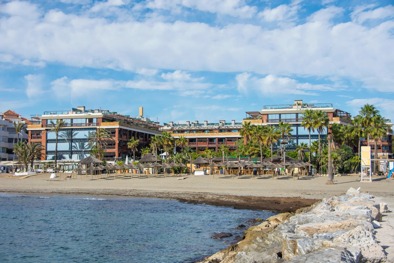 Charming beachfront resort in Marbella, Andalucía, Spain with palm trees and blue sky.