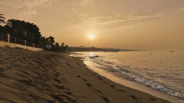 Serene sunset view over Marbella's sandy coastline with gentle waves.