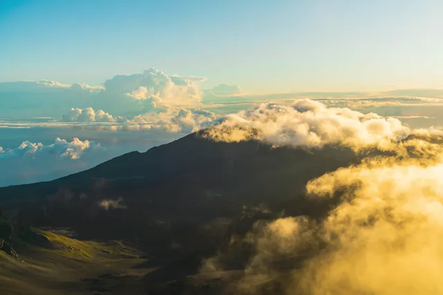 Stunning aerial view of Haleakala Volcano at sunrise with clouds enveloping the crater.
